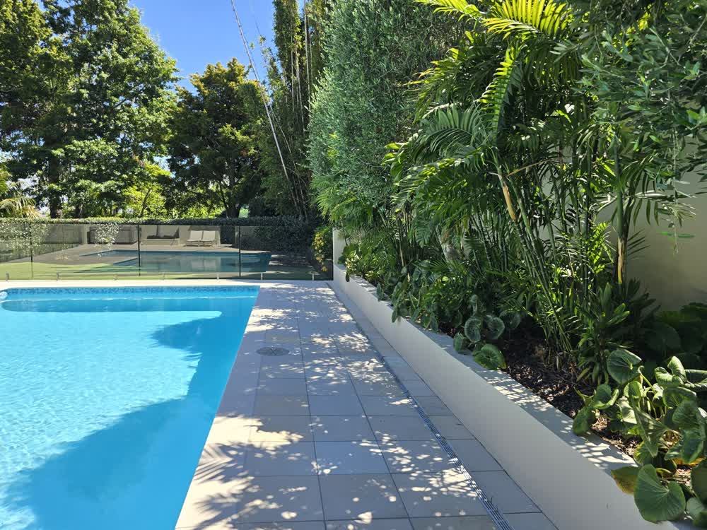Large pool with cream tiles and glass balustrade